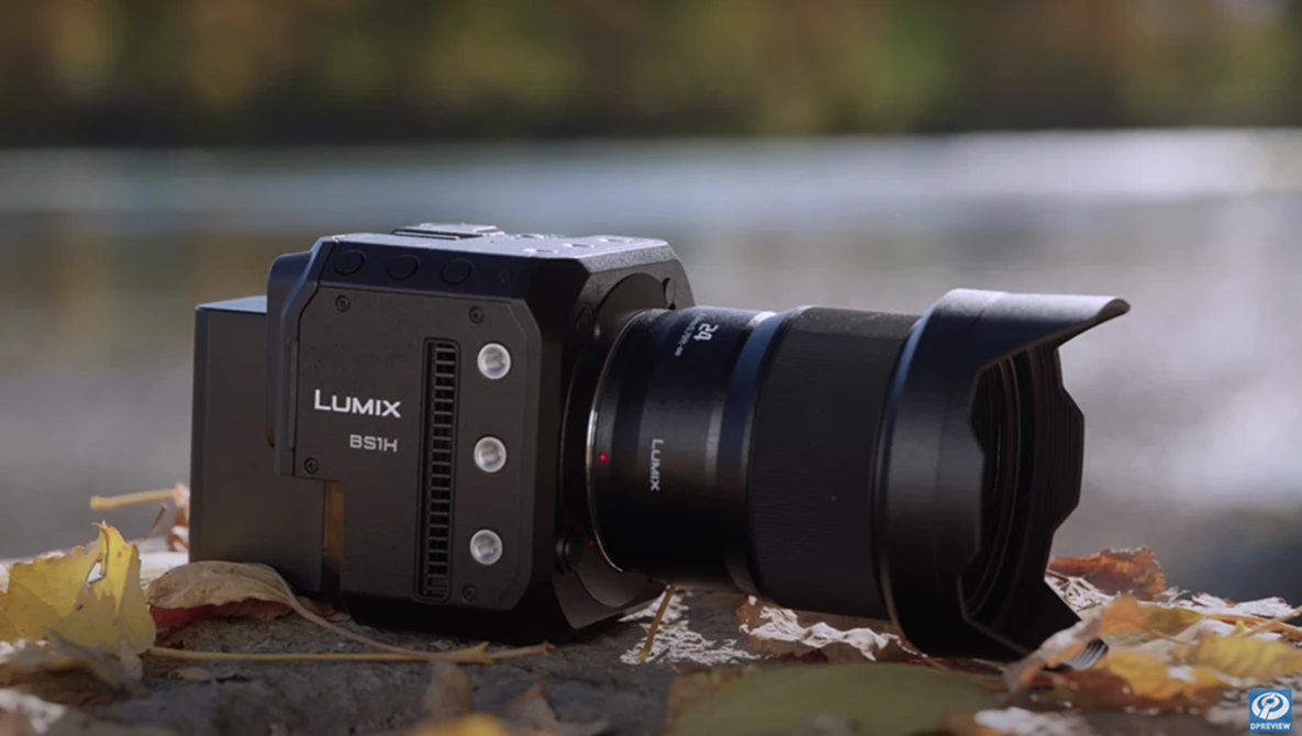 Panasonic Lumix S5H mirrorless camera with telephoto lens on autumn leaves by water.