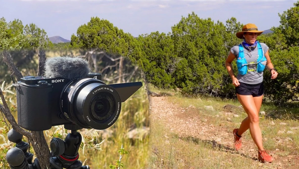 Sony camera on tripod mounted in foreground with trail runner in blue vest jogging on desert path behind.