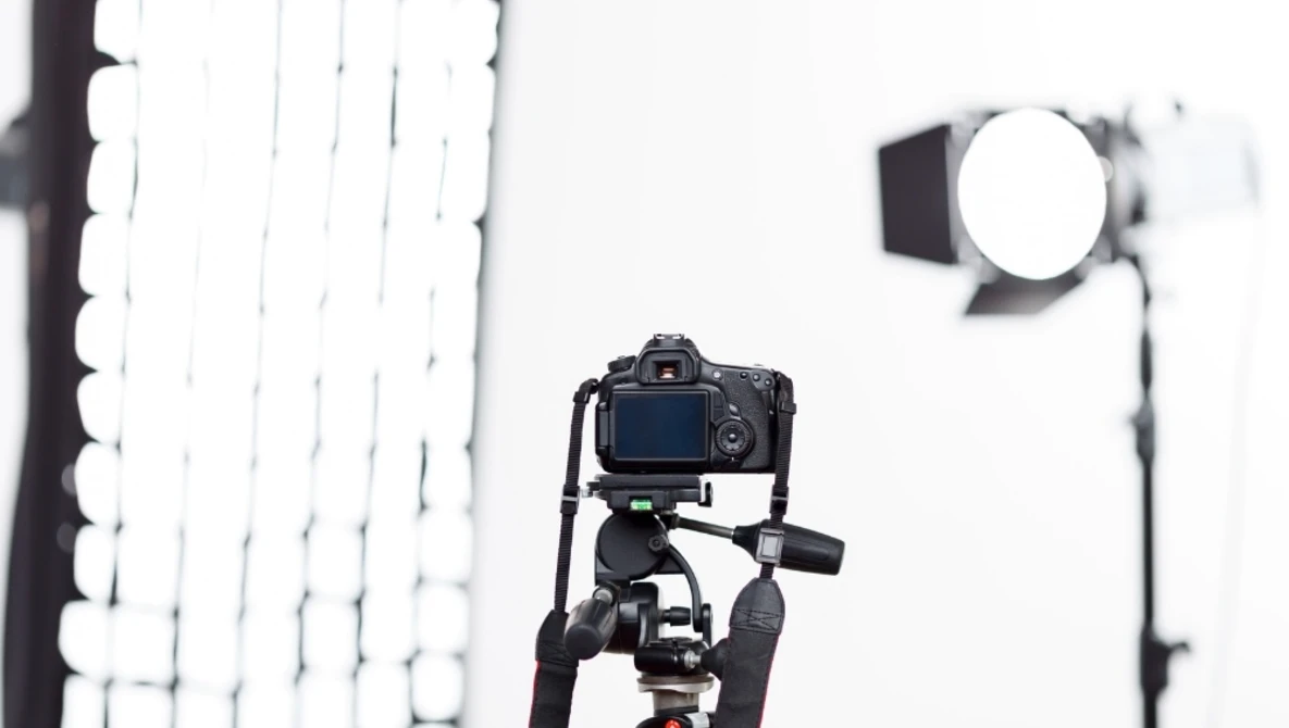 DSLR camera mounted on tripod with studio lighting setup in background.