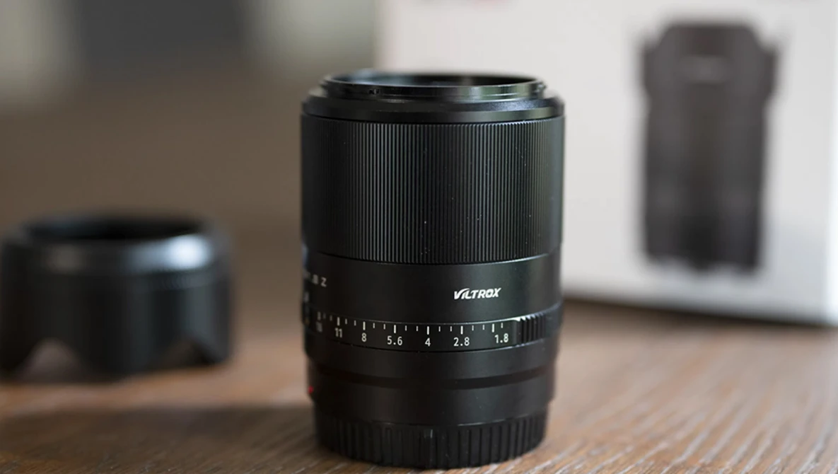 Viltrox prime lens with focus ring and aperture scale on wooden surface.