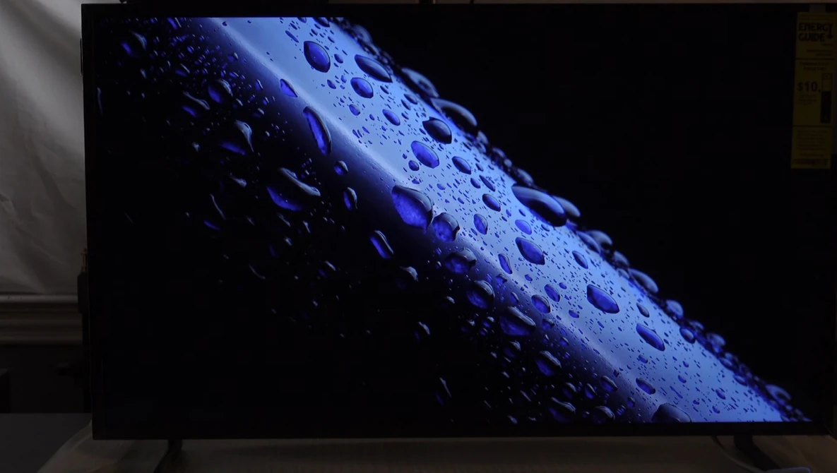 Water droplets on a blue cylindrical surface against a dark background, angled diagonally across frame.