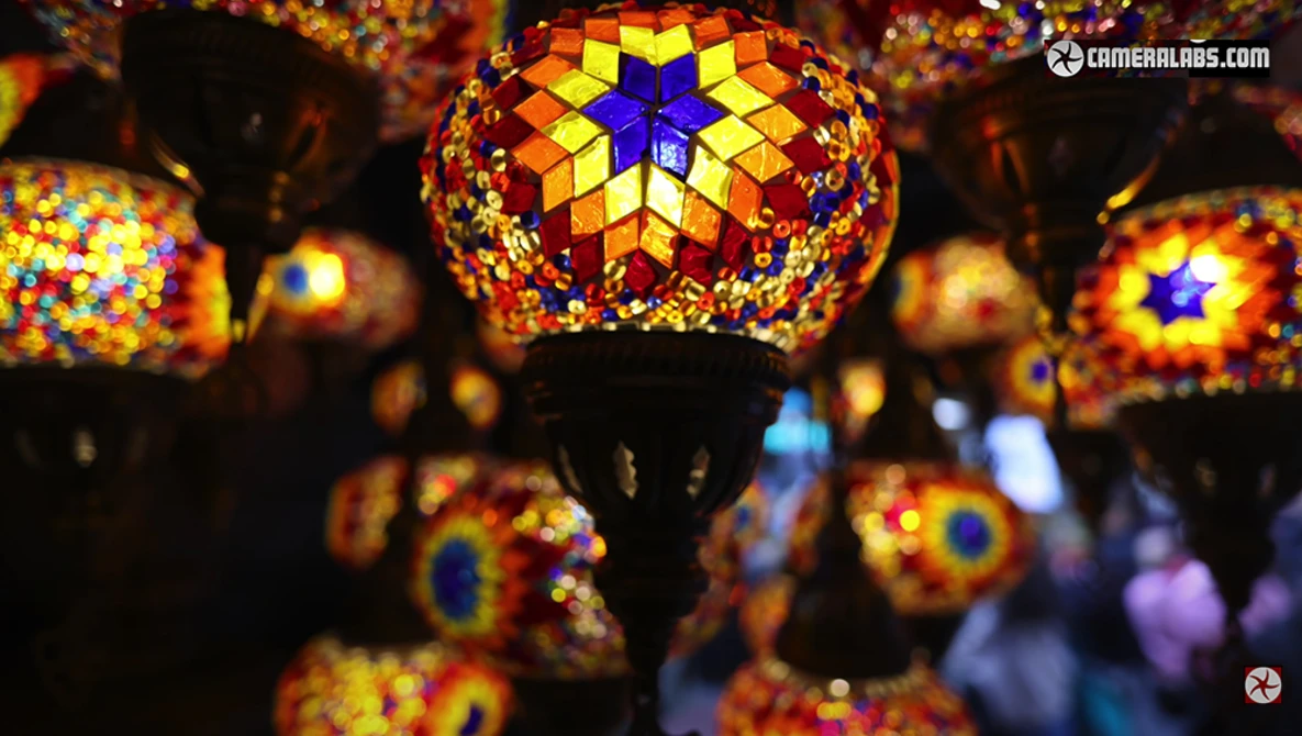 Ornate hanging lanterns with geometric stained glass patterns in warm gold and jewel tones, focused on a central blue star design.