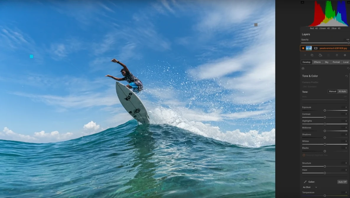 Surfer riding a wave with water spray, photographed from water level with editing software visible on right side.