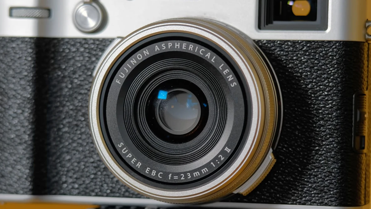 Close-up of a rangefinder camera's lens assembly showing a Chinon Aspherical lens with Super EBC 1:2.3 23mm focal length.