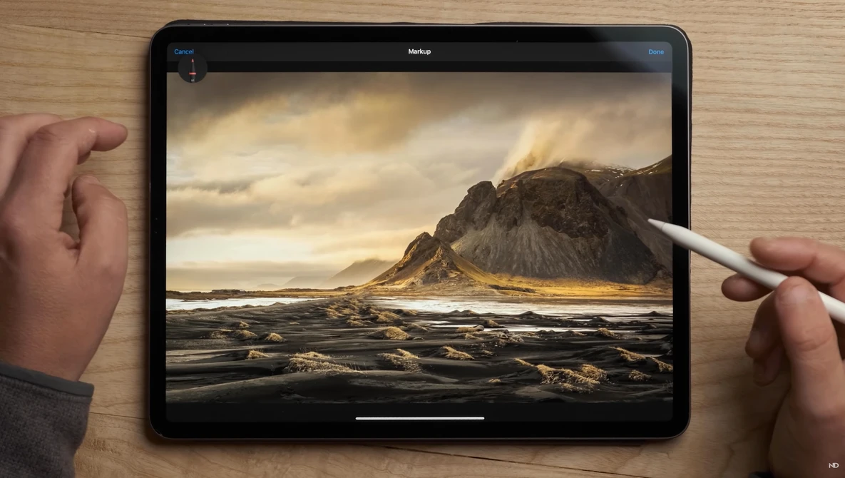 iPad displaying a dramatic Icelandic landscape with a dark mountain peak, black sand beach, and golden-hour lighting, being edited with an Apple Pencil.