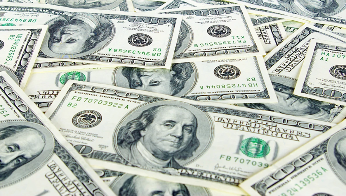 Multiple U.S. one hundred dollar bills scattered and overlapping, showing portrait sides.