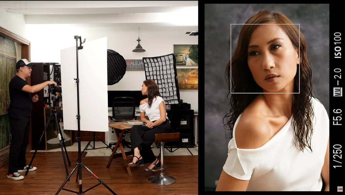 Professional portrait lighting setup in a studio with a model seated and photographer adjusting softbox equipment.