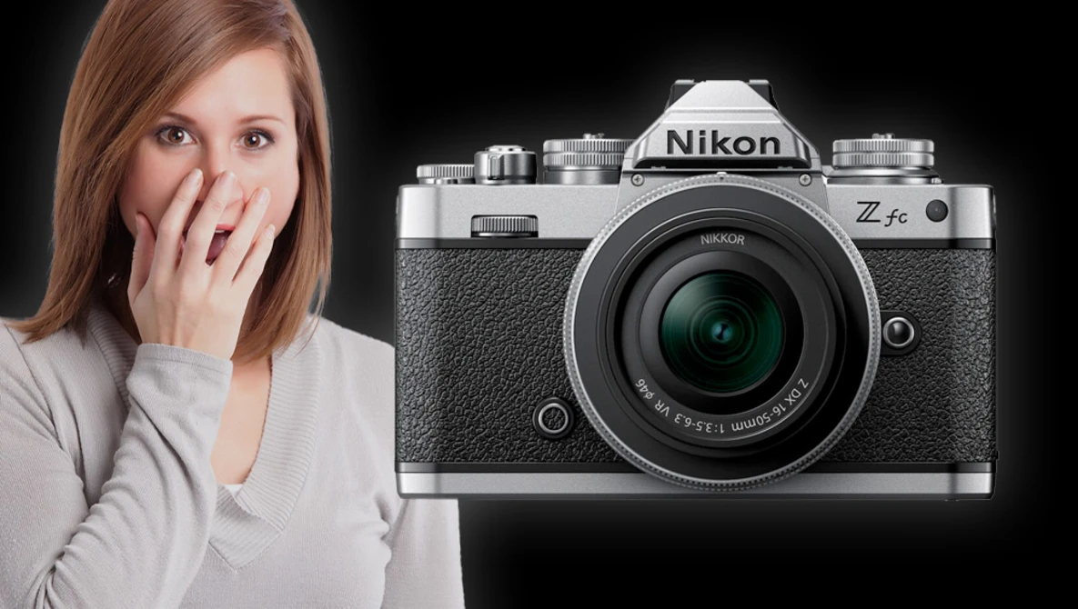 Woman with surprised expression beside a Nikon Z fc mirrorless camera on black background.