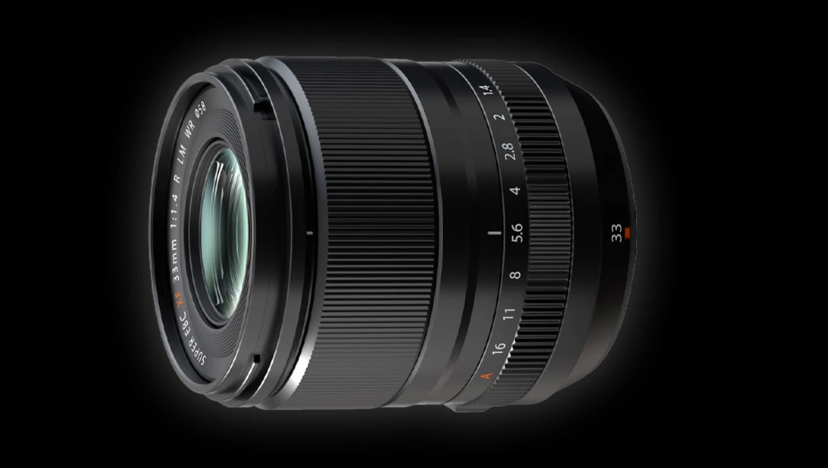 Black camera lens with focus and aperture rings against a dark background.