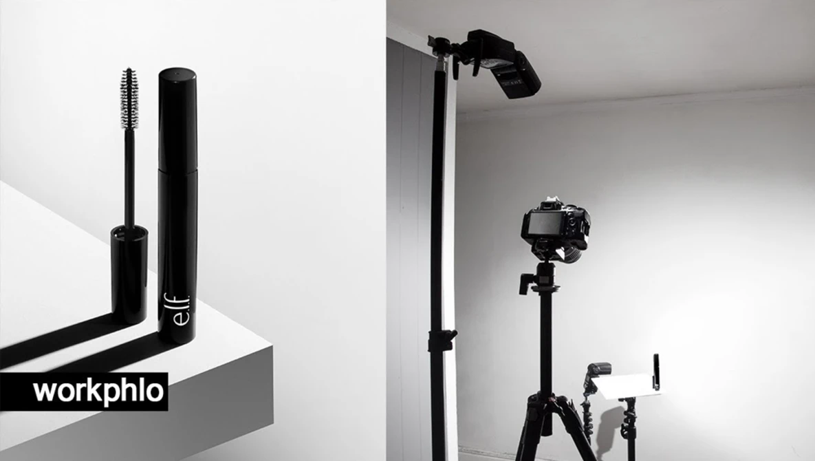 Mascara wand and tube displayed on a geometric surface against a white background.