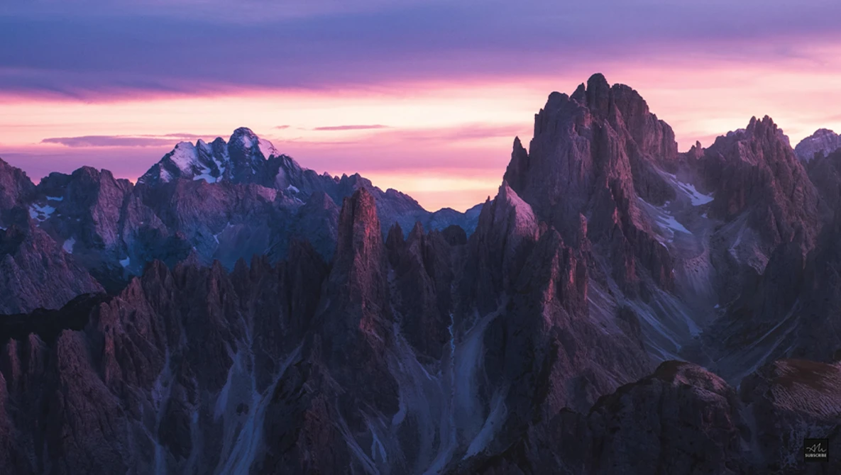 Jagged mountain peaks silhouetted against a dramatic purple and pink sunset sky.
