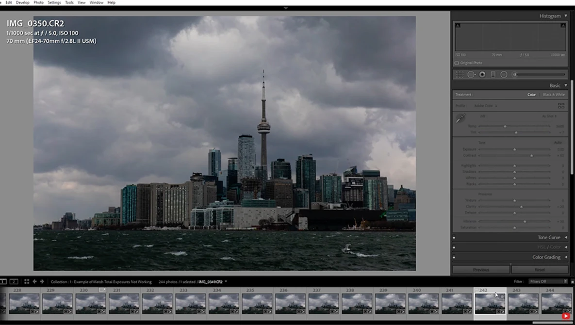 Toronto skyline with CN Tower viewed across Lake Ontario under dramatic cloudy sky.