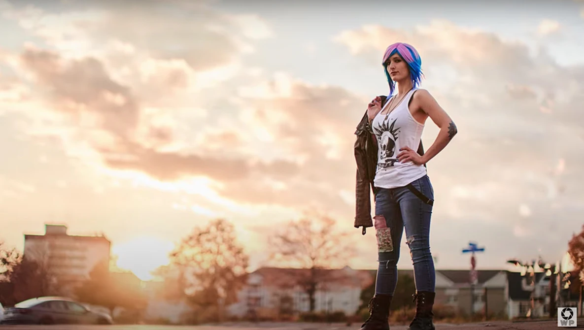 Woman with purple hair standing confidently in an urban plaza at golden hour.