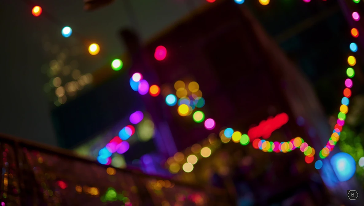Out-of-focus string lights in multiple colors creating bokeh effect against dark background.
