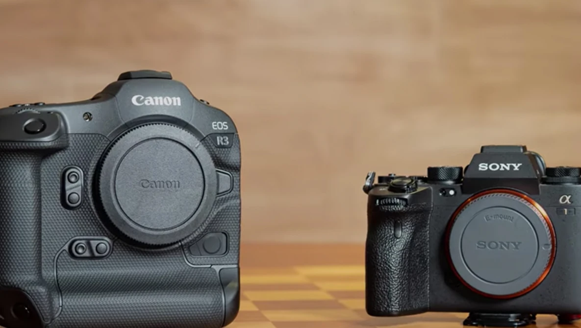 Canon EOS R3 and Sony Alpha camera bodies positioned side-by-side against a warm-toned backdrop.