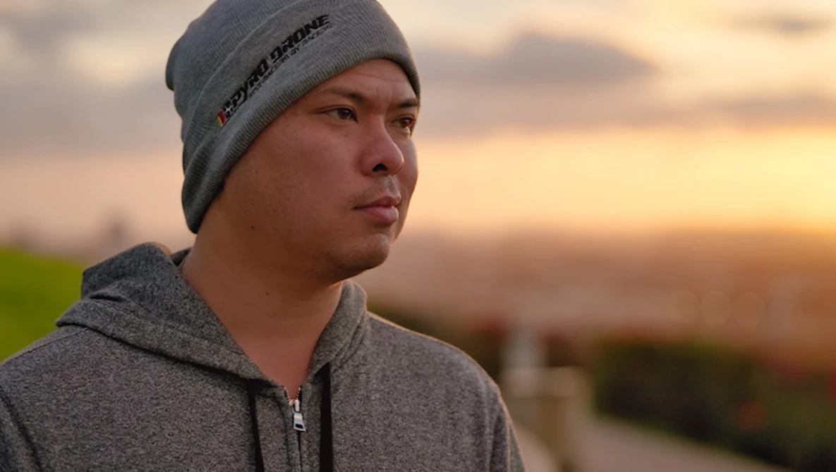 Young man in gray beanie and hoodie gazing to the side during golden hour sunset.
