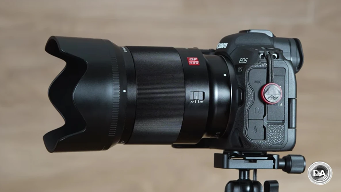 Mirrorless camera with telephoto lens and lens hood mounted on tripod ball head.