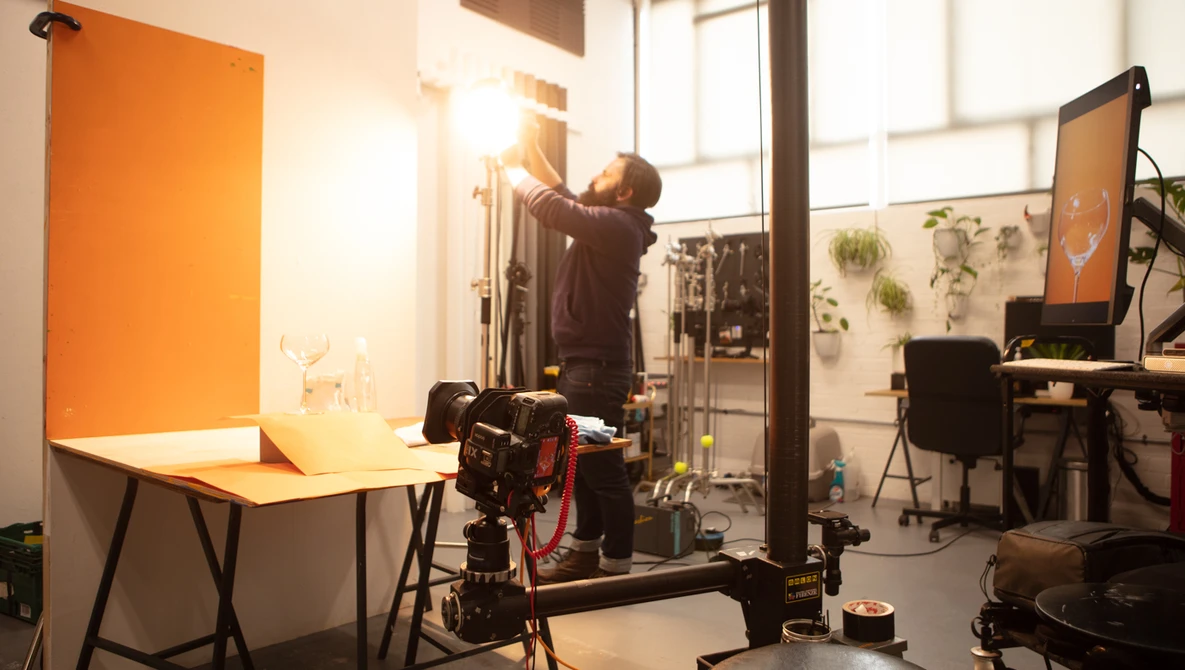 Professional photography studio setup with product photography lighting rig and orange backdrop.