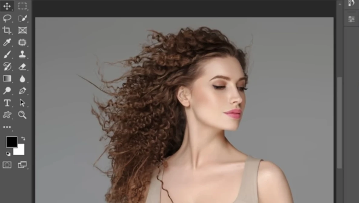 Woman with long, curly brown hair in profile against neutral gray background.