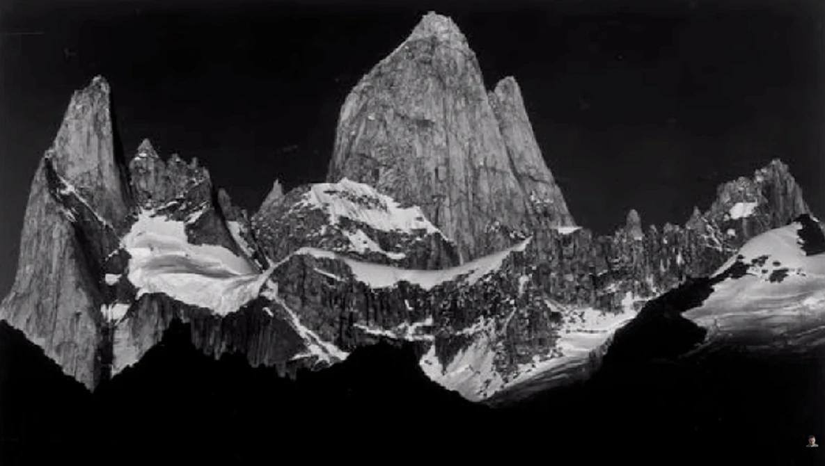 Black and white mountain landscape featuring dramatic granite peaks with glaciers and snow fields against dark sky.