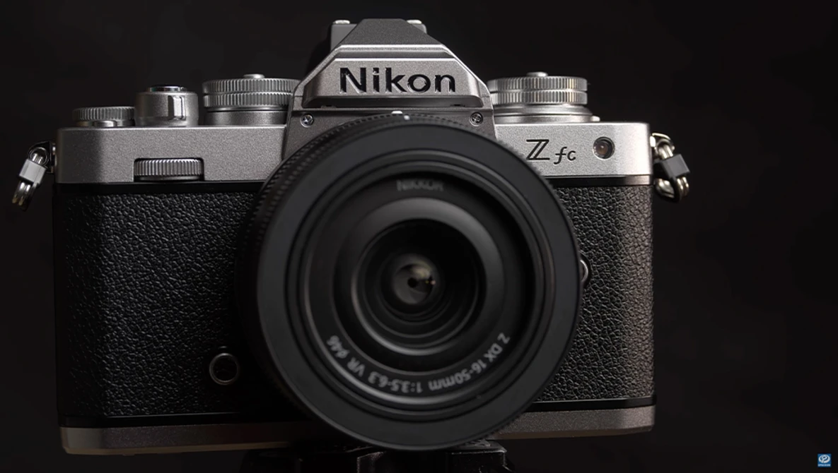 Nikon Z fc mirrorless camera with mounted lens on black background.