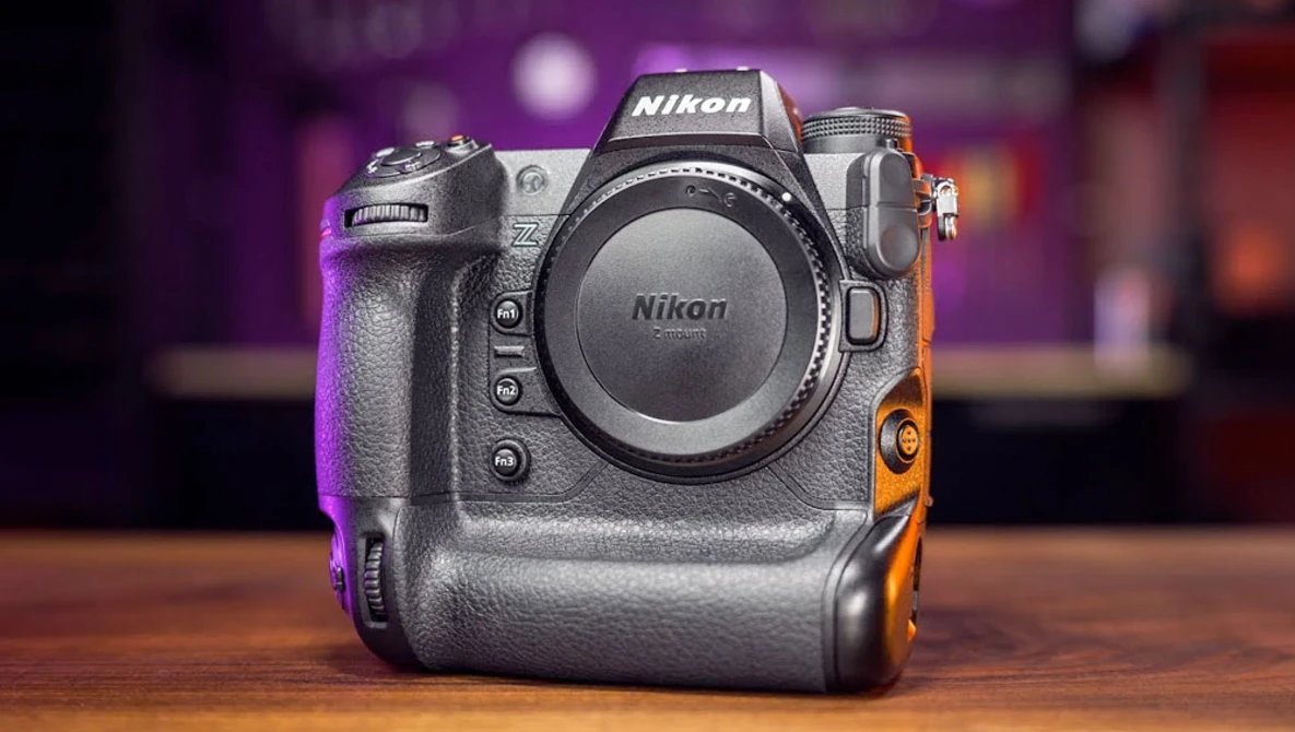Nikon Z9 mirrorless camera body displayed on wooden surface against blurred colorful background.