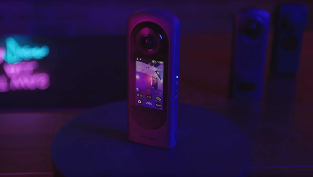 Smartphone displaying a purple-toned interface surrounded by neon blue and pink lighting in a dark environment.