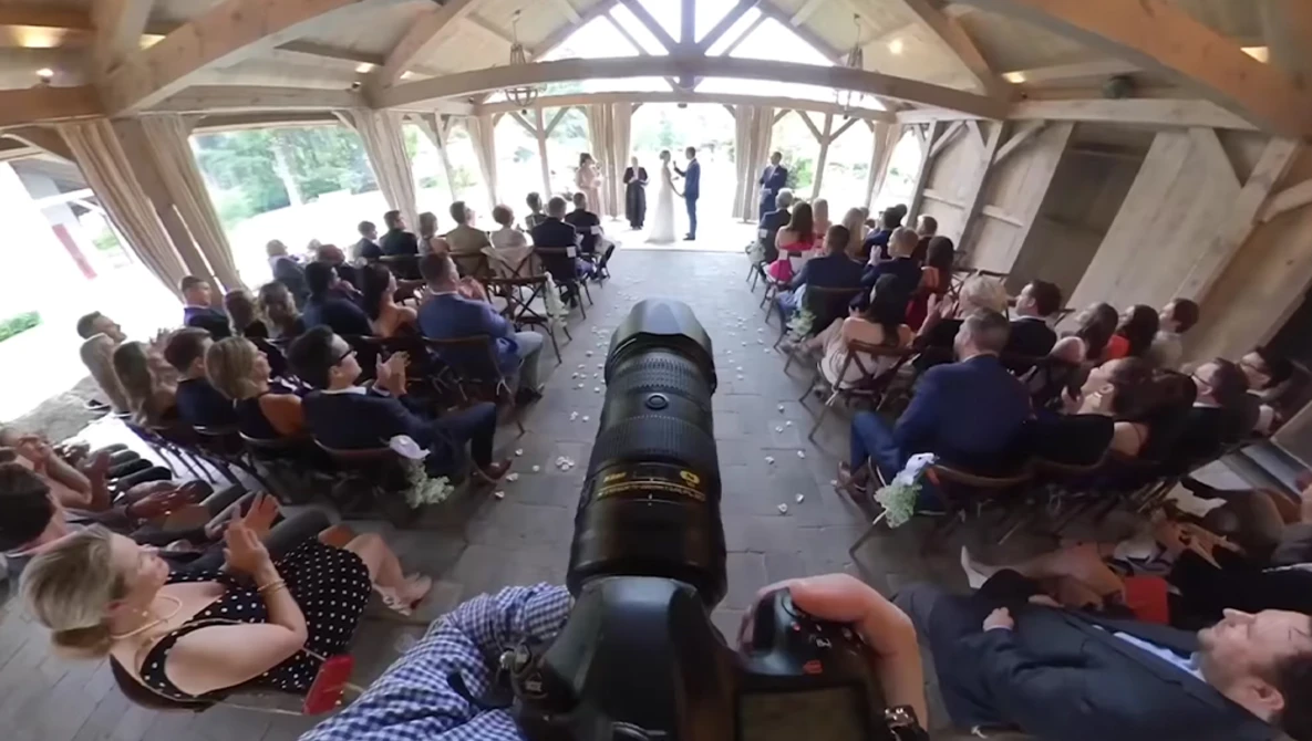 Overhead view of an antique cannon centered in a tent filled with seated spectators on both sides.