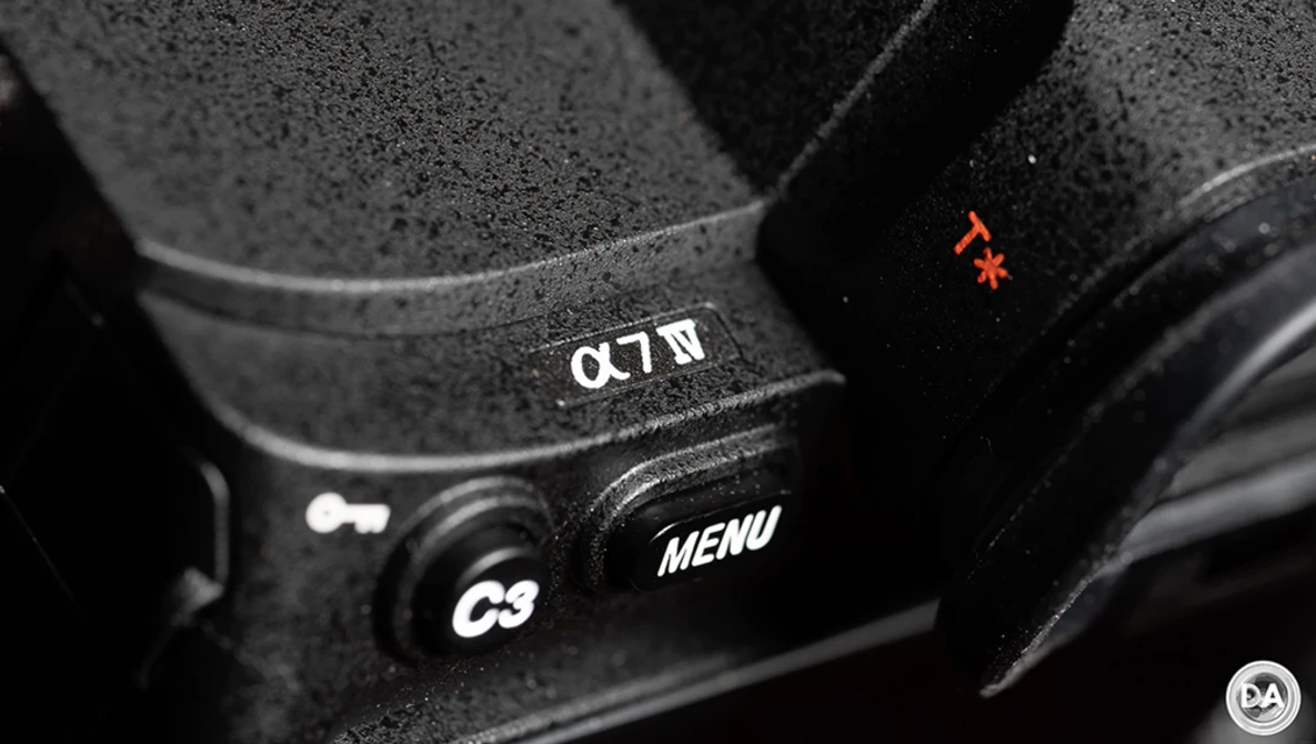 Close-up of camera controls showing α7 IV model designation, C3 button, MENU button, and status indicator light.