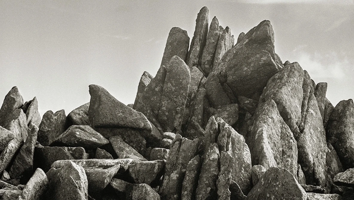 Dramatic rock formations with jagged, angular peaks against overcast sky.