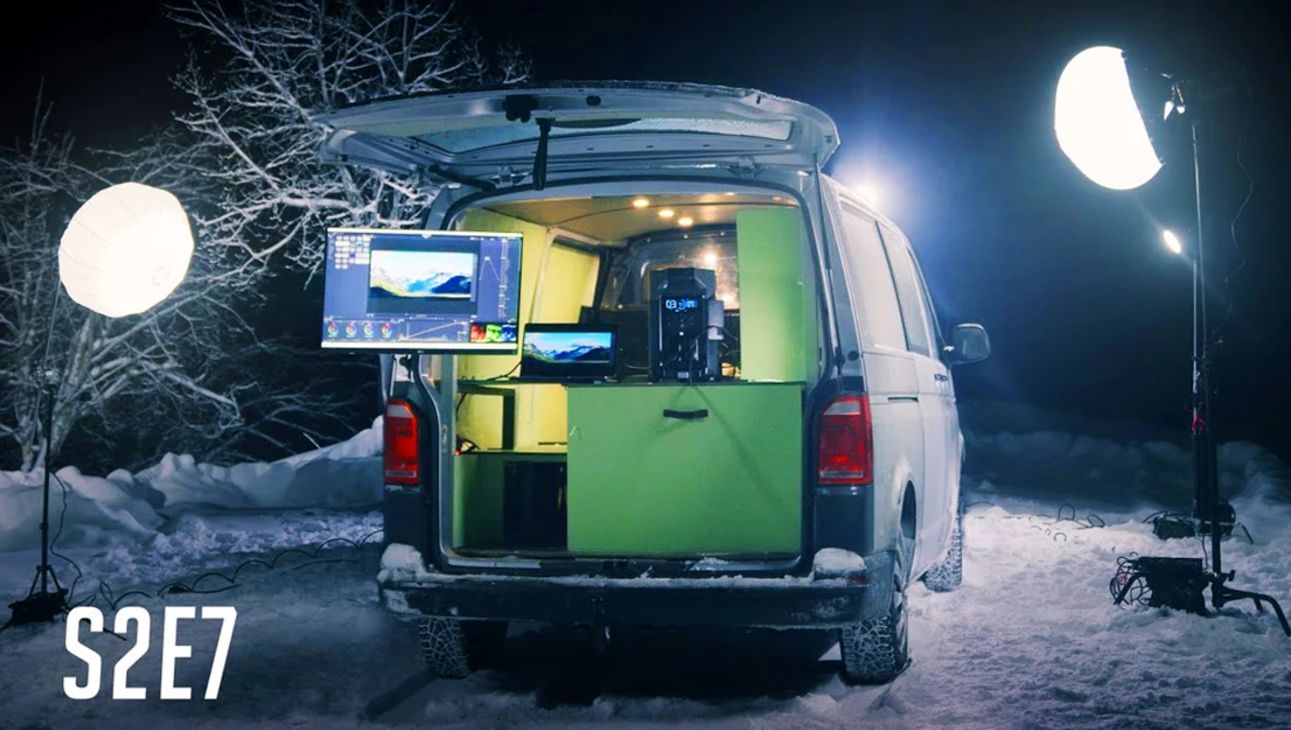 Mobile production van with green interior illuminated at night, surrounded by large LED lighting rigs on stands.