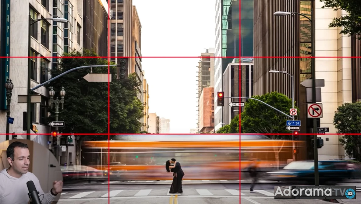 Urban street scene with motion-blurred bus crossing intersection between tall buildings.