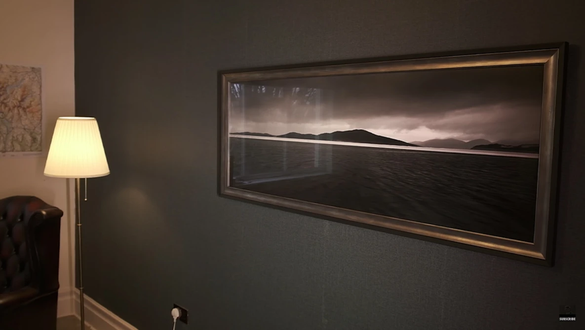 Framed black and white landscape photograph displayed in an interior wall, showing a minimalist composition of water, horizon line, and distant mountains.