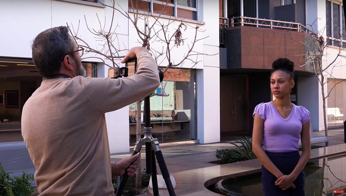 Photographer directing a female model during an outdoor portrait shoot in an urban setting.