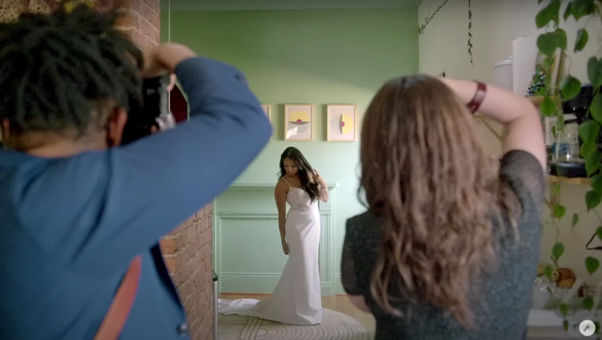 Photographer shooting a portrait of a woman in a white dress in a green studio room.