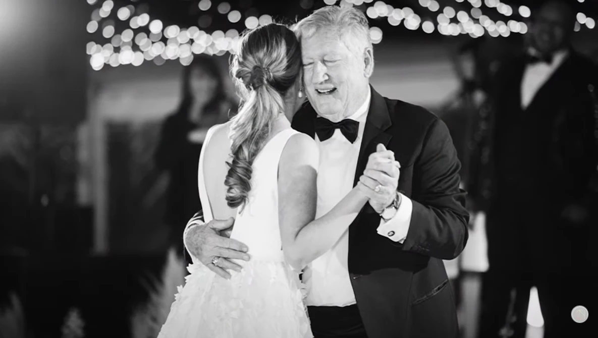 Bride and groom dancing together during first dance at wedding reception under string lights.