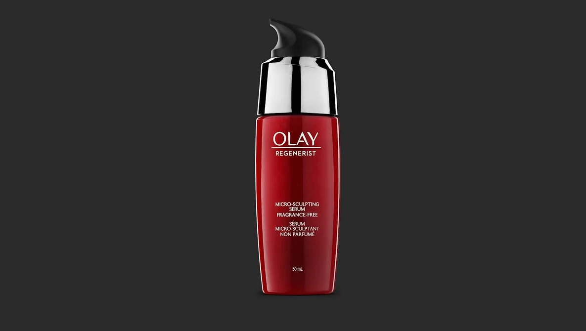 Red cosmetic bottle with silver cap against dark gray background.