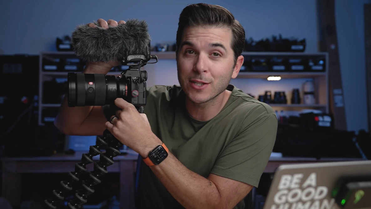 Videographer holding a professional cinema camera with shotgun microphone in a studio setting.