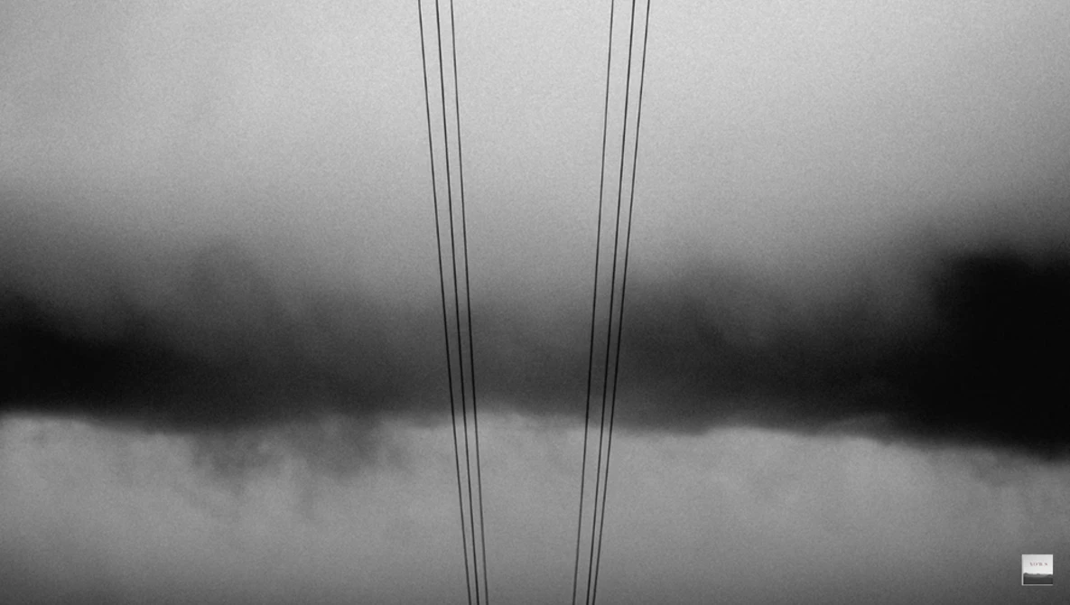 Two parallel power lines against a dramatic cloudy sky in black and white.