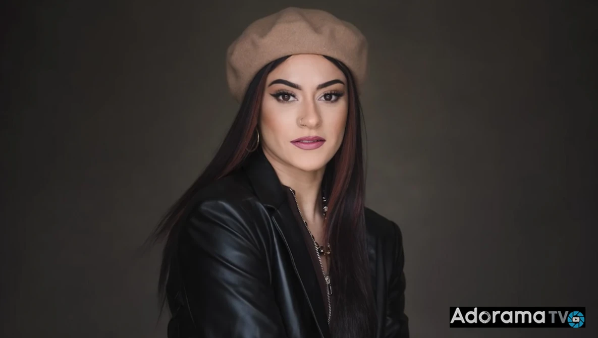 Woman wearing a beige beret and black leather jacket against a dark neutral background.