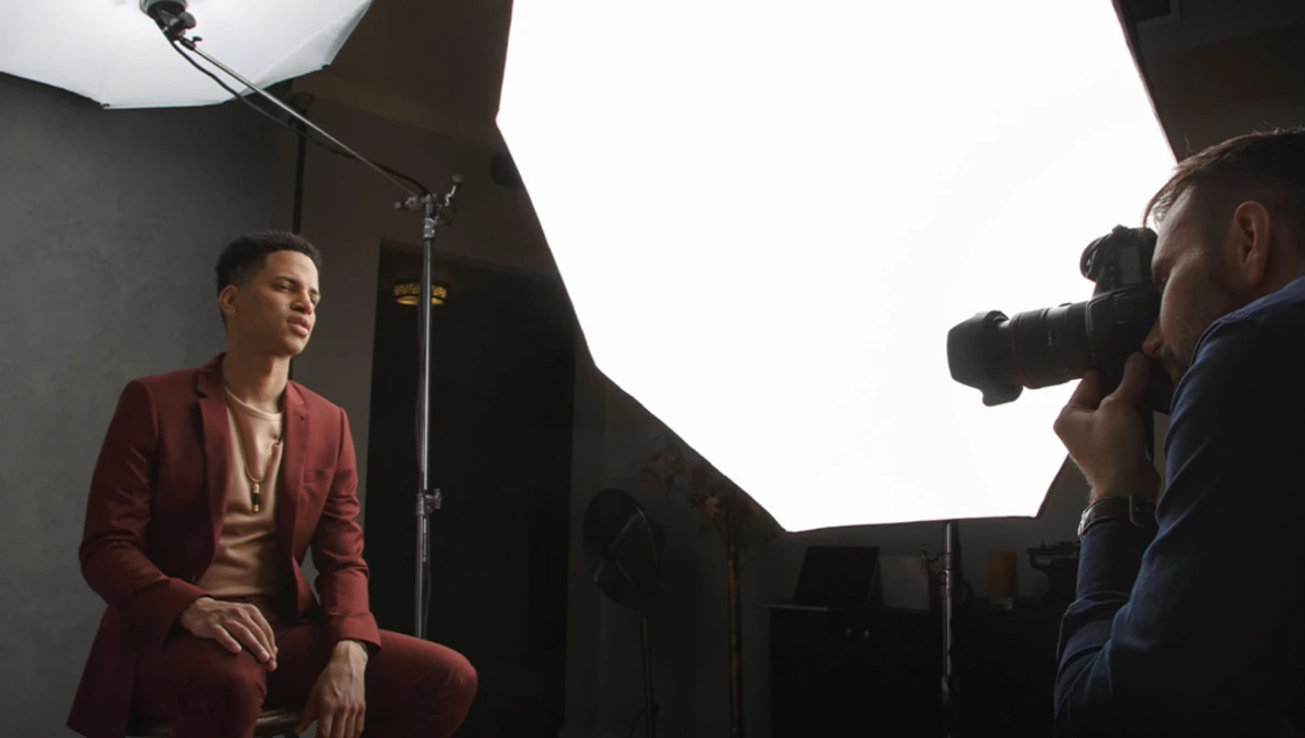 Man in burgundy blazer seated during professional portrait photography session with studio lighting.
