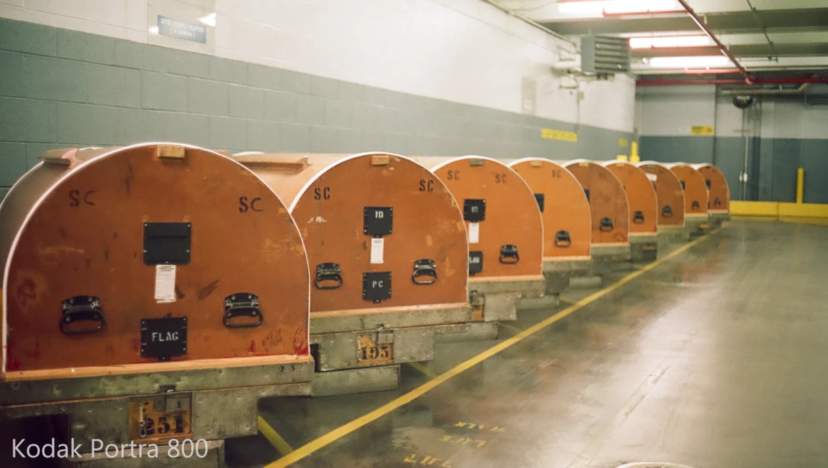 Row of orange metallic pressure vessels or tanks lined up in an industrial facility with green walls.