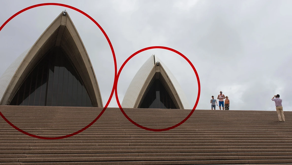 Red circles overlaid on architectural photograph highlighting two shell-shaped structures on a building's roof.