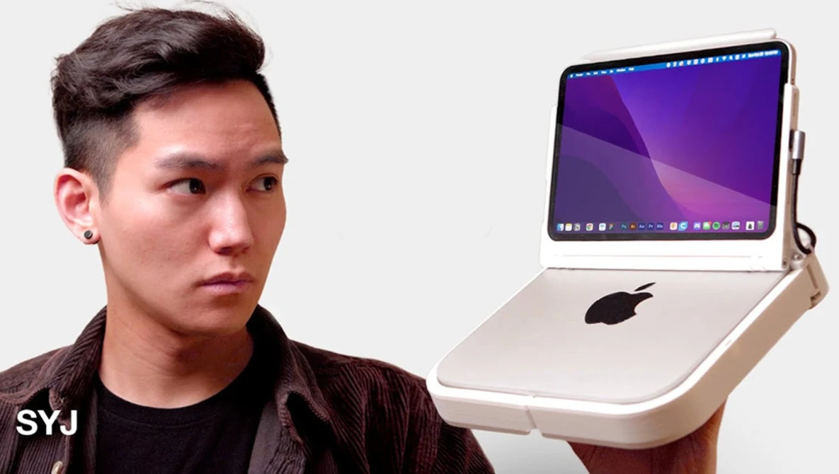Man in dark clothing holding a laptop with a purple display screen and tilted stand.
