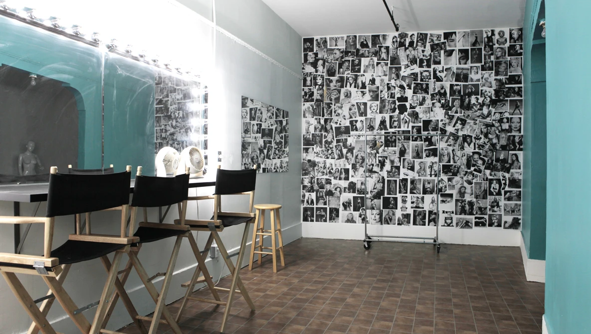 Modern interior space with turquoise accent walls, director's chairs, and gallery wall of black and white photographs.