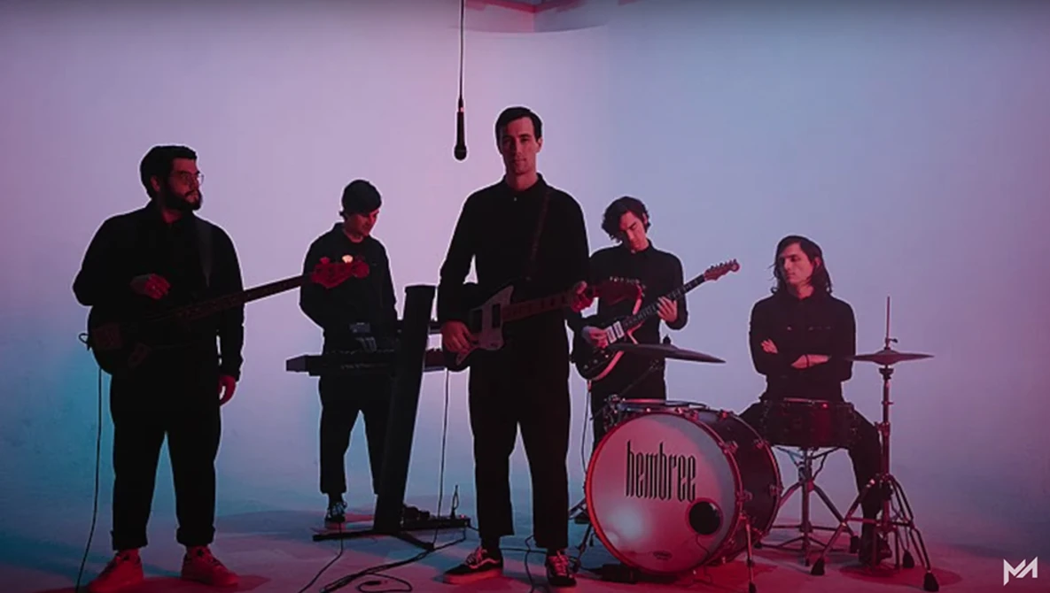 Five-piece band performing on stage with purple and blue gradient lighting.