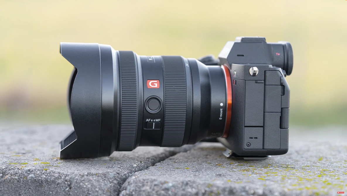Sony mirrorless camera with ultra-wide zoom lens and lens hood mounted on concrete surface.