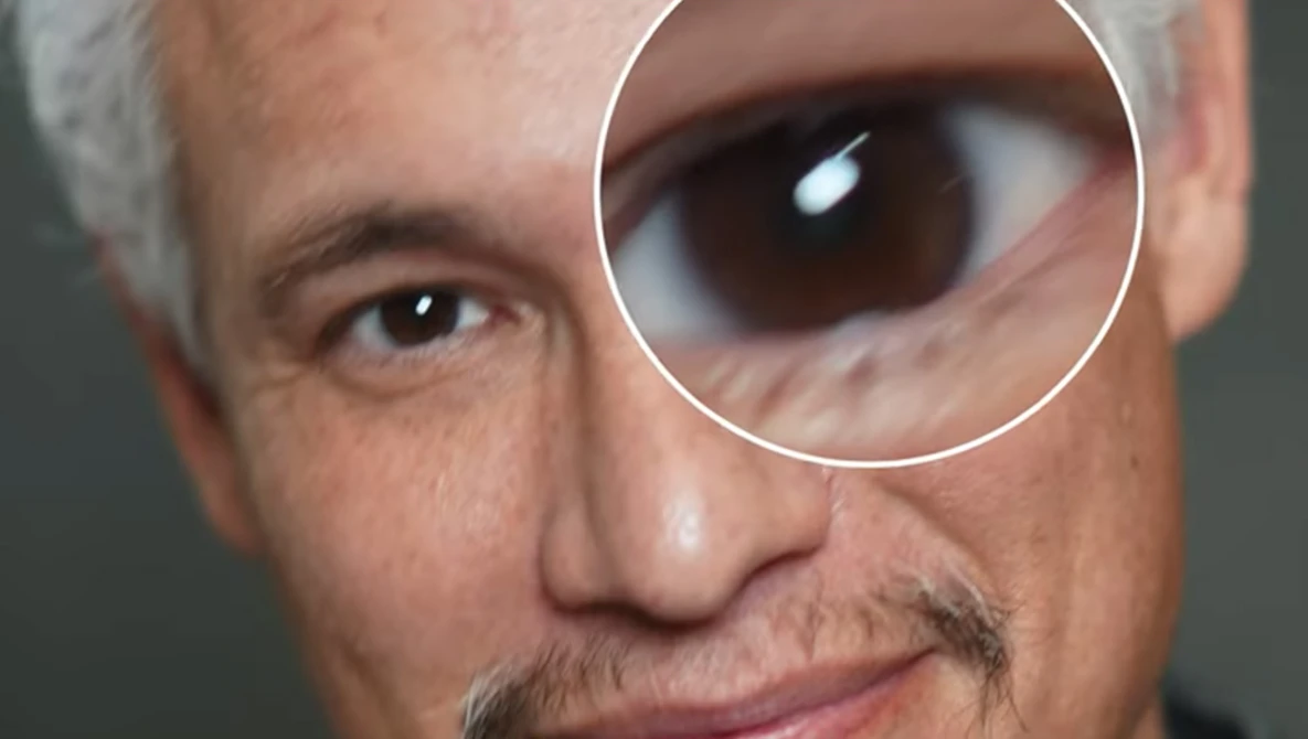 Close-up portrait of a man's face with a magnified circular inset showing extreme detail of his eye.