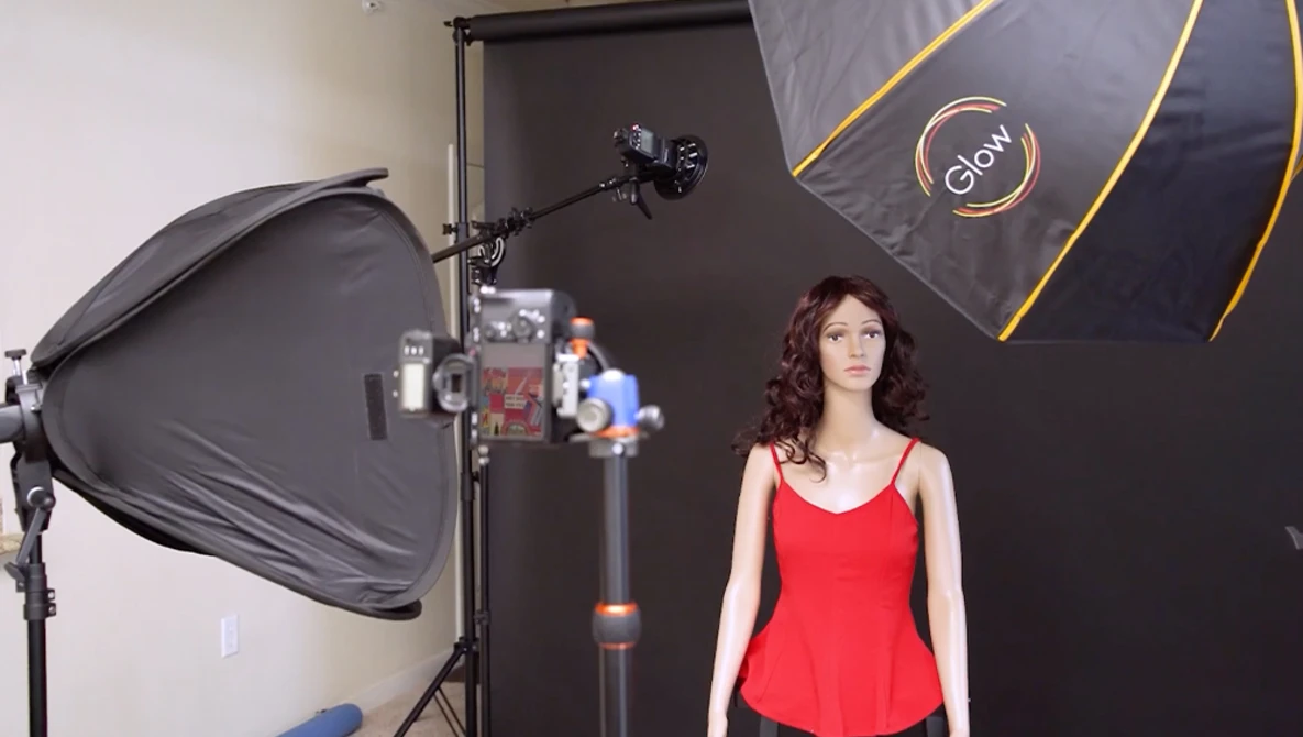 Woman in red tank top poses in professional studio with softbox and key light setup.