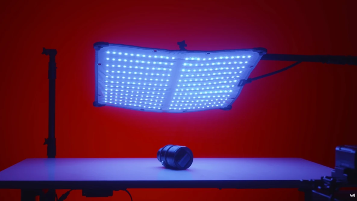 Blue LED panel light suspended above a table with a spherical object in moody red and blue studio lighting.